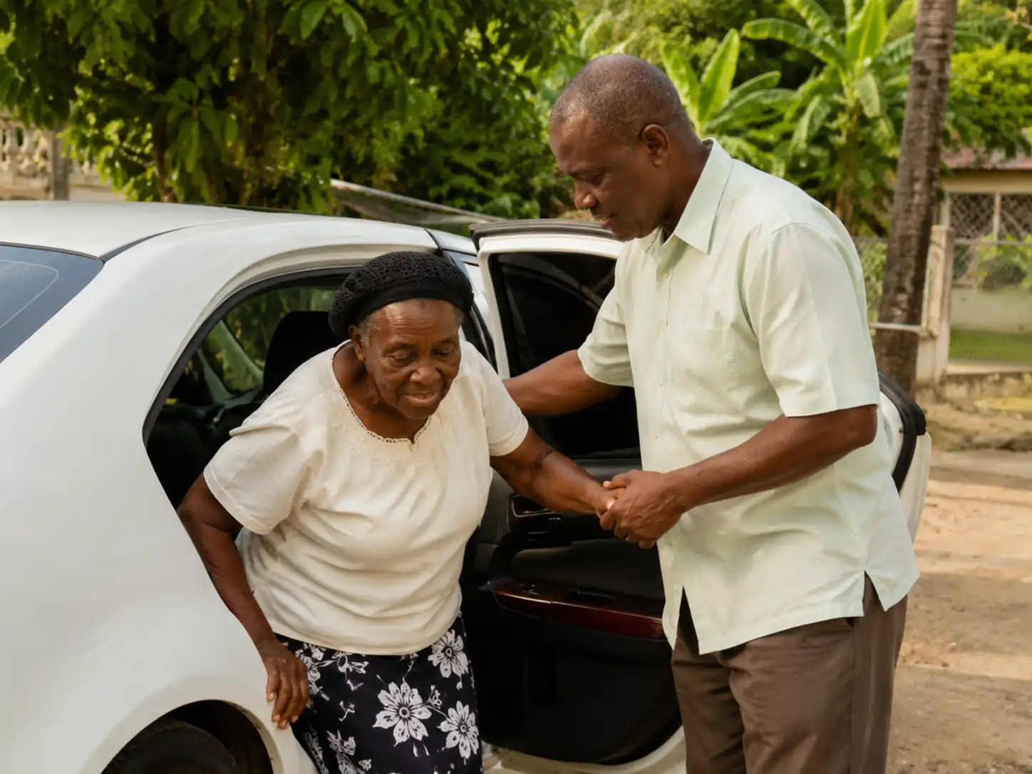 Older Jamaican parent being assisted into a private vehicle by a trusted companion